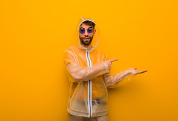 Young man wearing a rain coat holding something with hand © Asier
