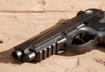 Black air gun on the wooden background.