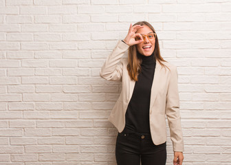 Young pretty business entrepreneur woman confident doing ok gesture on eye