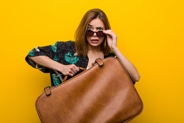 Young woman holding a leather bag  scared about her vacations, she has fobia to fly.