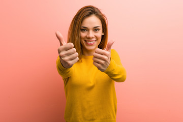 Young pretty young woman with thumbs ups, cheers about something, support and respect concept.