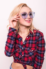 Cute amazed blonde girl tourist in shirt, holding her trendy glasses on white background