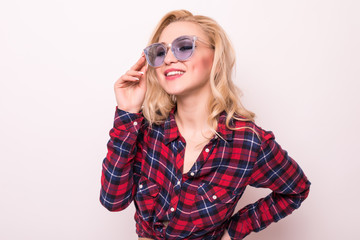 Obraz premium Pretty young woman in checkered shirt wearing trendy sunglasses smiling at camera isolated on white background