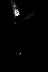 Faucet leaking water to black background. Macro detail of drop of water being wasted