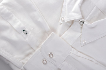 Close up of the neck, sleeves and buttons of a white shirt.