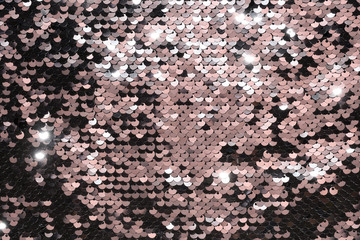 Sequin fabric background. Close-up shot of glittery black sequins texture reflecting red light