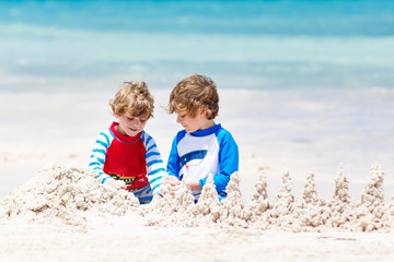 Two kid boys building sand castle on tropical beach of Playa del Carmen, Mexico