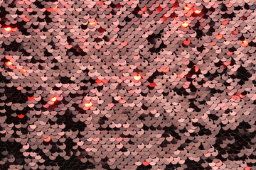 Sequin fabric background. Close-up shot of glittery black sequins texture reflecting red light