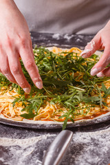 Fototapeta na wymiar young woman in a gray aprong prepares a vegetarian pizza