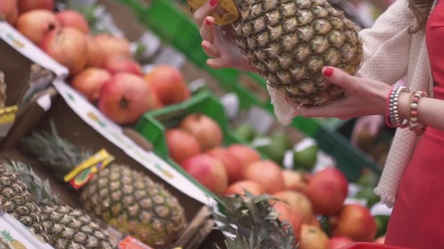  Close up, supermarket, market, grocery store slender attractive girl woman chooses colorful fruits vegetables pineapple and puts in the basket, the concept of healthy food and lifestyle