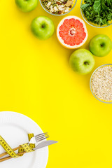Weight loss concept with green organic food on yellow background top view space for text