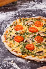 young woman in a gray aprong prepares a vegetarian pizza