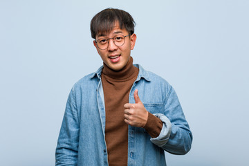 Young chinese man smiling and raising thumb up