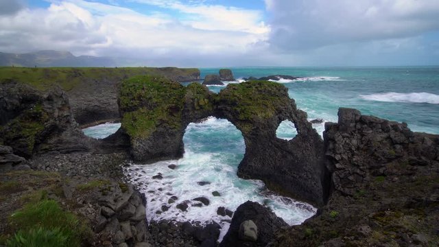 Amazing stone arch Gatklettur basalt rock on Atlantic coast of Arnarstapi in Iceland. The famous natural form arch attracts tourist to visit west of Iceland.