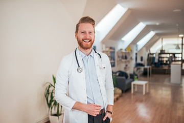 Portrait of young cheerful doctor in bright office.