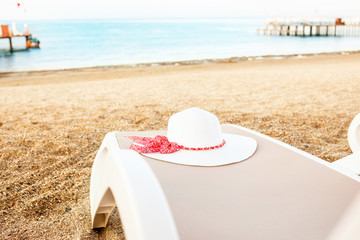 Fototapeta na wymiar White summer hat laying on deck chair.