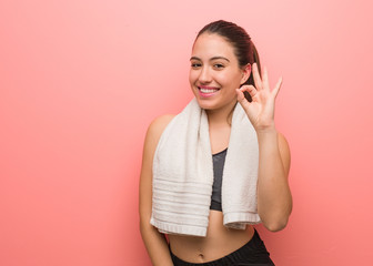 Young fitness woman cheerful and confident doing ok gesture