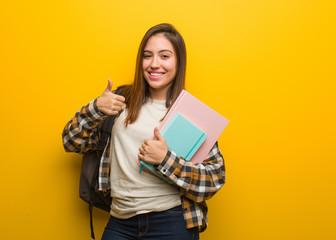 Young student woman smiling and raising thumb up