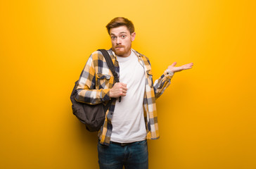 Young redhead student man confused and doubtful