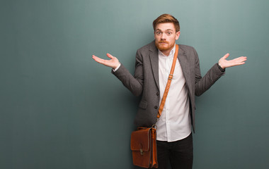 Young redhead business man confused and doubtful