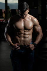 Fototapeta na wymiar Young Bodybuilder In Jeans Flexing Muscles