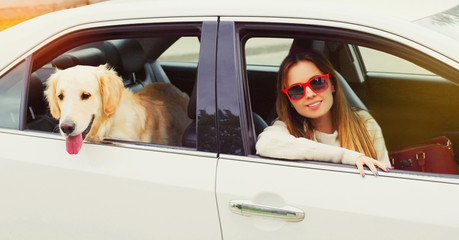 Happy woman and Golden Retriever dog sitting in car looking out the window