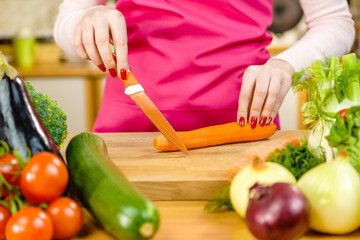 Woman cutting carrot on kitchen board