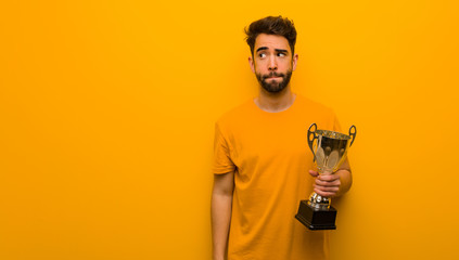Young man holding a trophy thinking about an idea