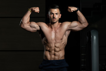 Fototapeta na wymiar Bodybuilder Performing Front Double Biceps Pose In Gym