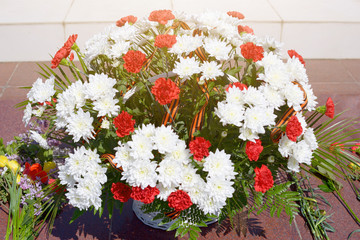 Fototapeta na wymiar May 9, Victory Day. Flower arrangement of red carnations and St. George ribbon as a gratitude to the fallen soldiers at the memorial to the fallen soldiers of the war of 1941-1945 .