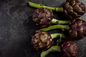 Obraz premium Purple artichokes flowers heads on dark slate