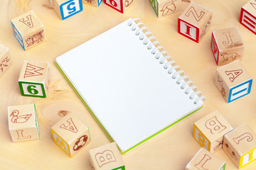 Notepad on wooden table and wood alphabet blocks