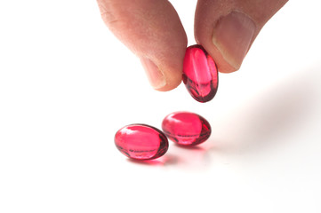 closeup of red pills in hand on white background