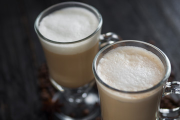 Coffee with milk in a glass on dark wooden background