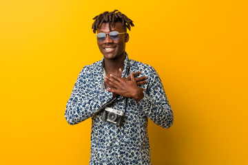 Young black rasta man wearing a vacation look laughing keeping hands on heart, concept of happiness.