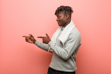 Young fitness african black man excited pointing with forefingers away.