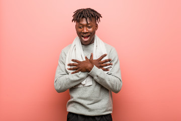 Obraz premium Young fitness african black man laughing keeping hands on heart, concept of happiness.