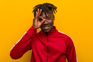 Young fitness african man excited keeping ok gesture on eye.