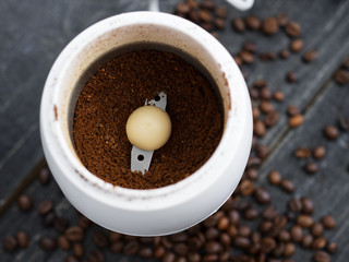 Coffee grinder on a dark wooden table with roasted coffee beans