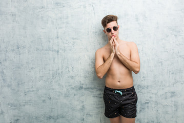Young caucasian man wearing swimsuit making up plan in mind, setting up an idea.