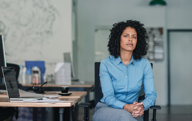 Confident young businesswoman sitting at her desk in an office