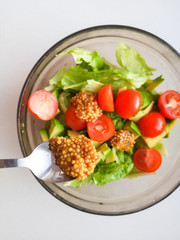 Seasoning for vegetable salad, adding French mustard to vegetable salad, Vigatarian food, healthy food. Female cook pouring olive oil in fresh vegetable salad seasoning it