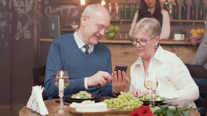Senior man showing something on his phone to his wife in a restaurant