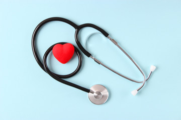 Stethoscope and heart on wooden color background. Health, medicine