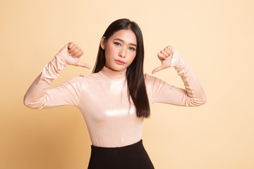 Fototapeta premium Unhappy Asian girl show thumbs down with both hands.