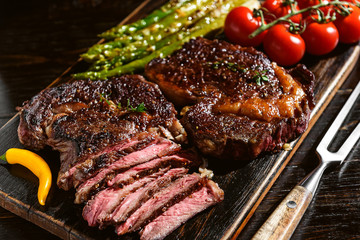Dinner for two juicy delicious steaks, asparagus with parmesan and vegetables.