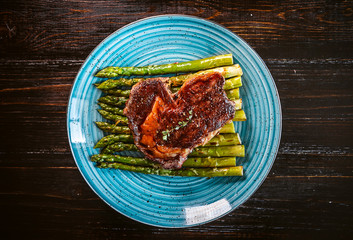 tasty and juicy steak and asparagus half fried in a frying pan and sprinkled with grated Parmesan cheese