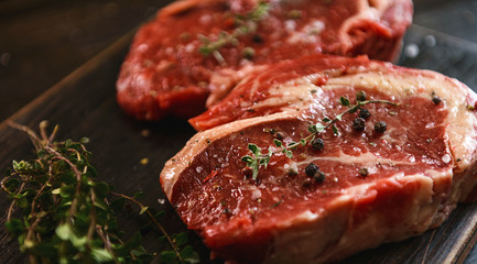 two raw marbled beef steaks in olive oil and spices ready for frying. dinner party concept
