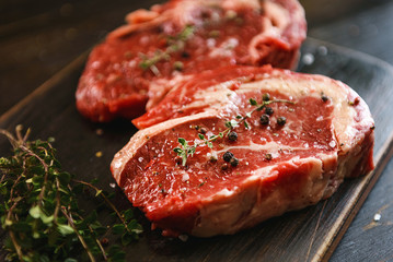 two raw marbled beef steaks in olive oil and spices ready for frying. dinner party concept