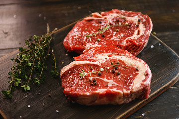 two raw marbled beef steaks in olive oil and spices ready for frying. dinner party concept